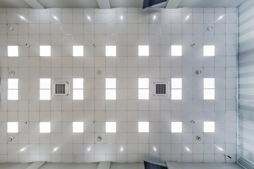 cassette stretched or suspended ceiling with square halogen spots lamps and drywall construction in empty room in house or office. Looking up view photo
