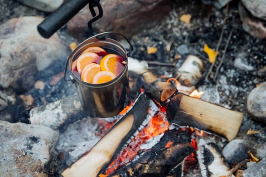 Fire with wood, fire burning, smoke, top view of how mulled wine drink is being prepared, heated wine, warm drink with spices, food in nature on a hike. photo