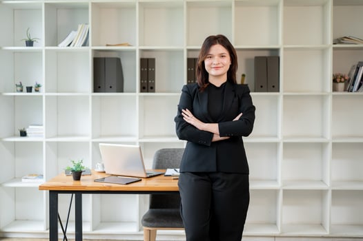 A confident businesswoman standing in her office with her arms crossed, looking at the camera. photo