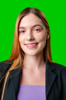 Young Woman Wearing Black Blazer and Purple Top Against Green Screen photo