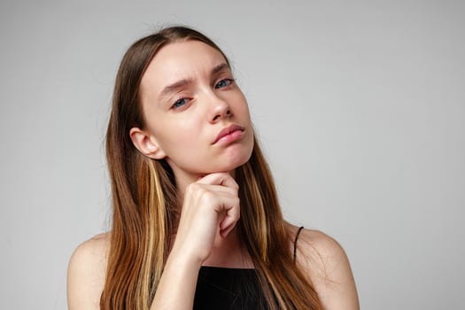 Young Woman With Long Brown Hair Posing Thoughtfully Against White Background photo