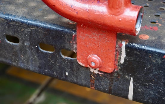 Heavy duty orange colored bolt metal connection on outdoor playground park toy fence and bridge equipment. photo