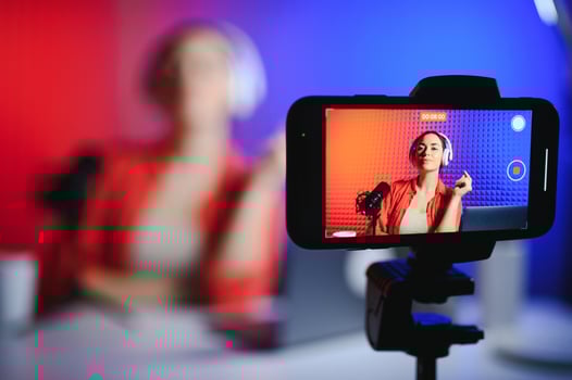 Young attractive woman blogger or vlogger looking at camera and talking on shooting with technology photo