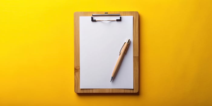 school, reminder, memo, organization,wood clipboard, Wooden clipboard with a blank sheet of white paper ready to be written on accompanied by a pen isolated on a vibrant yellow background photo