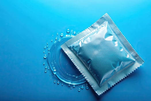 sexual health, sexual wellness, isolated, healthcare, contraception, barrier method, safer sex, Ribbed and dotted condom filled with water isolated on a blue background photo