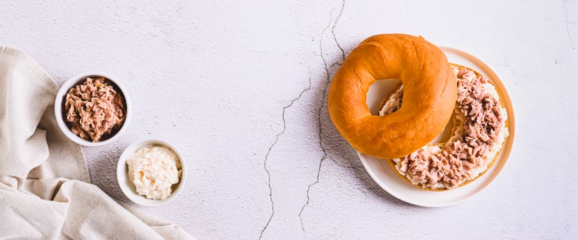 Hearty bagel burger with tuna and ricotta on a plate on the table top view web banner photo
