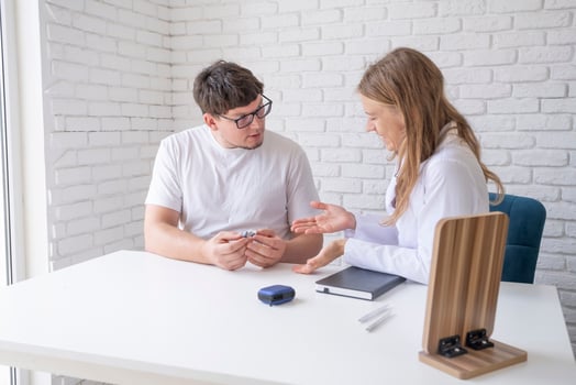 young male patient testing hearing aid in clinic exam room, female doctor helping photo