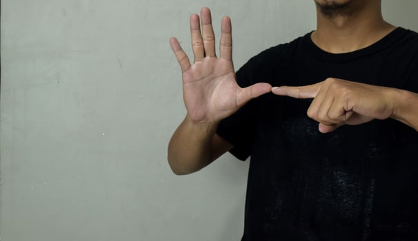young man showing hearing impaired gesture in sign language to communicate photo