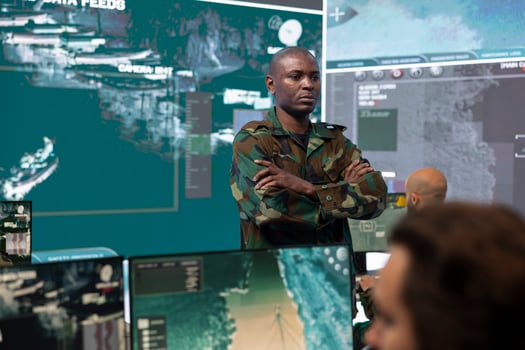 Portrait of army commander in military camouflage uniform supervising his crew, captain overseeing national safety operations in command post. Army officer works at federal agency base. photo