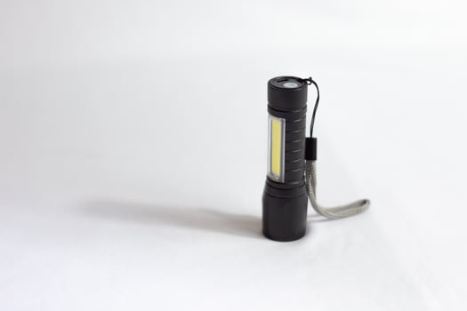 Modern black metal LED flashlight. Portable flashlight with white background. photo