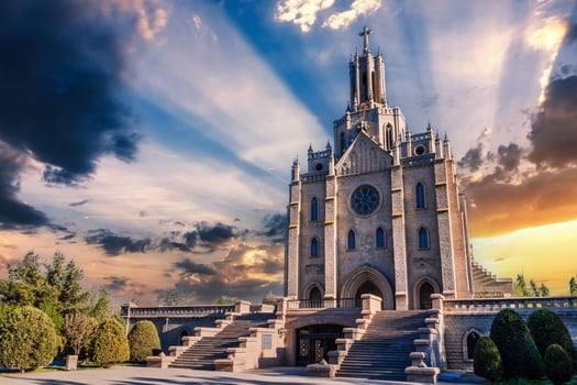 Ancient old stone Cathedral of Sacred Heart of Jesus in Tashkent in Uzbekistan. Facade of Catholic Church on background of cloudy beautiful sky at sunset in summer photo