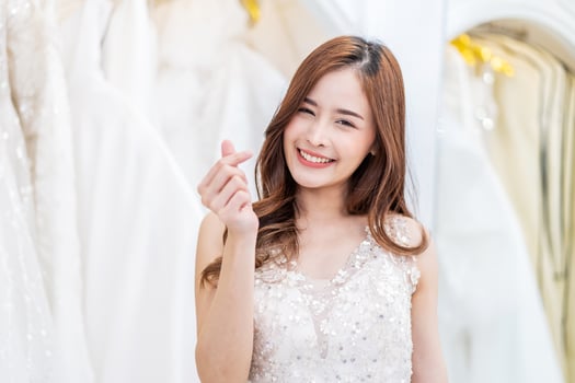 Portrait Young asian beautiful bride in white wedding dress standing posing with hand sign in meaning mini heart or love, Happy woman in wedding day theme concept photo