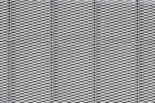 Steel surface with a repeated, geometric pattern of perforations resembling small, elongated diamond shapes. photo