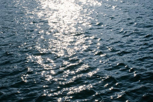 Sunset Reflections, Rippling Water Surface with Golden and Blue Hues at Evening sea wave abstract texture sunlight blue and golden pattern blurred background. photo