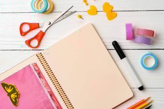 Creative workspace with open notebook, stationery, and decorative items on a wooden table photo