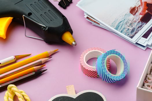 Crafting supplies arranged on a pink background, including glue gun, scissors, and decorative items for DIY projects photo