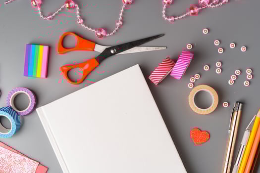 Crafting supplies arranged for a DIY project on a gray table with scissors, washi tape, and decorative items photo