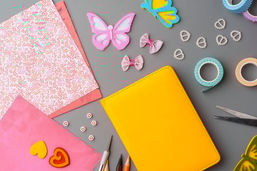 Crafting supplies arranged for a DIY project on a gray table with scissors, washi tape, and decorative items photo
