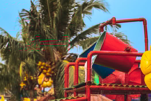 Water spills on the water bucket attraction in water park. Water splash on tipping bucket or water bucket in swimming pool. Water park and swimming pool rides. photo