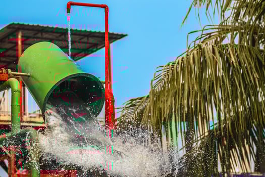 Water spills on the water bucket attraction in water park. Water splash on tipping bucket or water bucket in swimming pool. Water park and swimming pool rides. Freezing photo water splash.