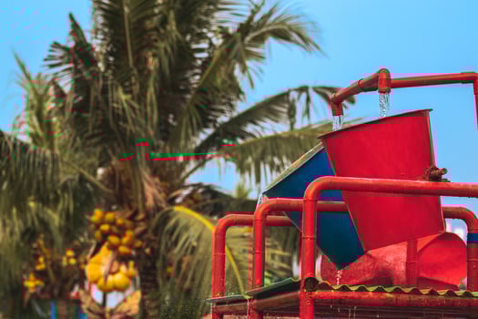 Water spill on water bucket attraction in water park. Water splash on tipping bucket or water bucket in swimming pool. Water park and swimming pool rides. photo