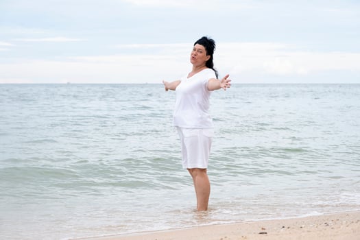 Happy mature woman with arms outstretched feeling the breeze at beach, feeling happy photo