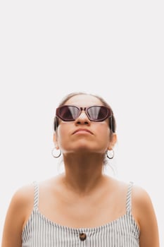 Woman with glasses in front of a white background and looking up photo