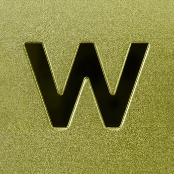 Letter W on a golden grained shiny metal surface. English alphabet. photo