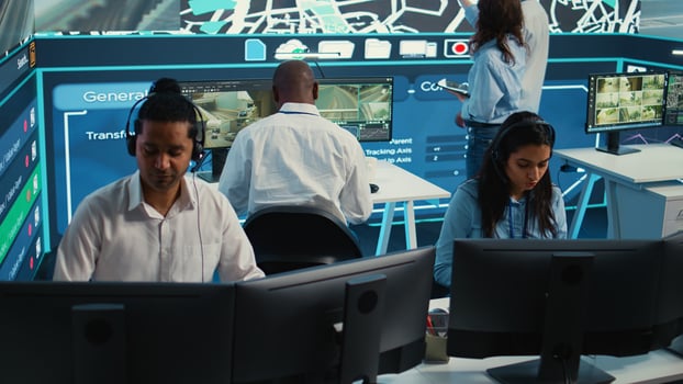 Indian woman dispatch operator gives directions to couriers, avoiding traffic by monitoring radar CCTV surveillance footage. Employee uses gps coordinates and satellite map. Camera B. photo