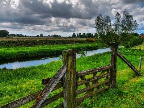 A wooden fence and a river in a field photo