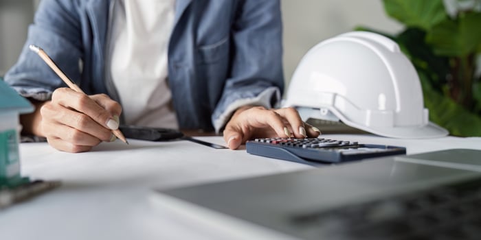 Engineer calculating project costs with calculator in office photo