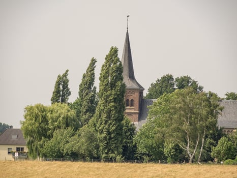 A church with a steeple and trees in the background at bislich photo