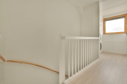 A white stairway with a window and a wooden railing photo