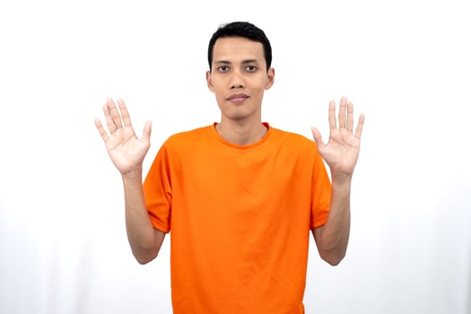 Portrait of a young Asian man wearing an orange t-shirt posing giving a warm greeting to a friend or customer. Isolated on white background. photo
