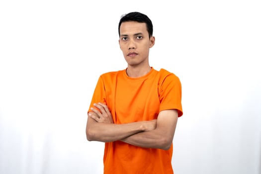 Portrait of a young Asian man wearing a colored t-shirt posing upright with his two arms crossed over his stomach. Isolated on a white background. photo