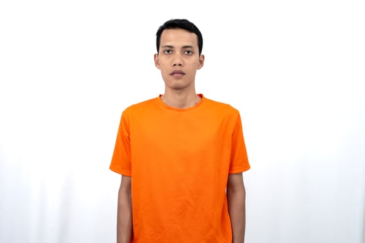 Portrait of a young Asian man wearing a colored t-shirt with a straight pose and a casual expression. Isolated on a white background. photo