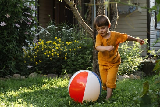 Summer outdoor activity. Kid playing with beach ball on lawn. photo