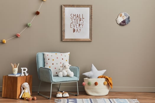 Cozy interior of child room with mint armchair, brown mock up poster frame, toys, teddy bear, plush animal, decoration and hanging cotton colorful balls. Beige wall and Warm kid space. photo