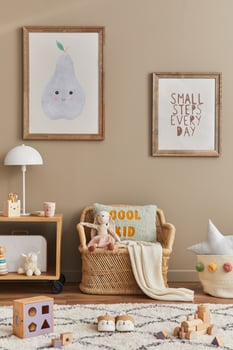 Stylish scandinavian kid room interior with toys, teddy bear, plush animal toys, rattan sofa, furniture, decoration and child accessories. Brown wooden mock up poster frames on the wall photo