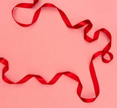 Red wavy ribbon on pink background. Holiday decoration. Valentine's Day decoration congratulation frame. photo