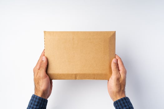 Male hand holding parcel post against white background photo