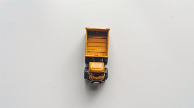 Bright yellow toy truck with an orange cargo hold on a white background photo