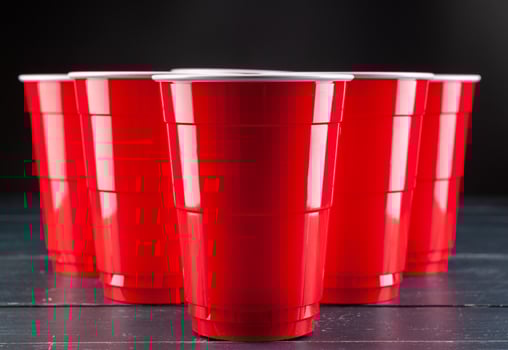 Wooden table with red cups and ball for beer pong photo
