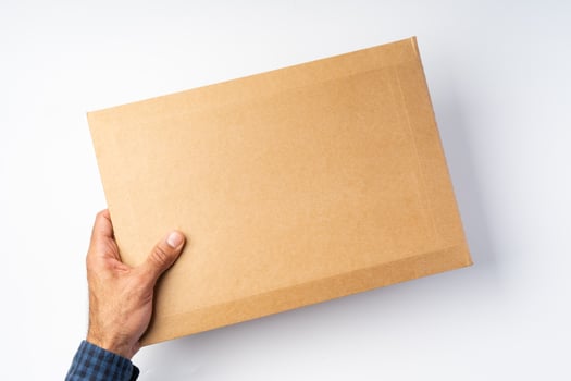 Male hand holding parcel post against white background photo