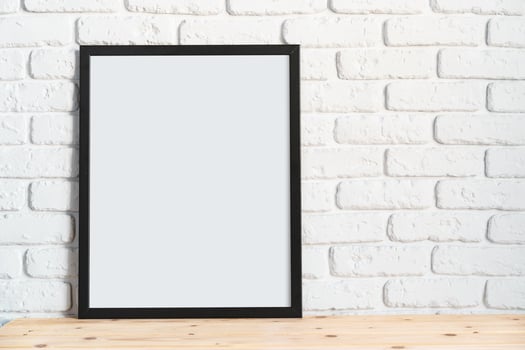 Photo frames on floor over white brick wall