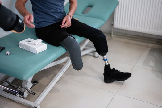 Man with prosthetic leg sitting on examination table photo