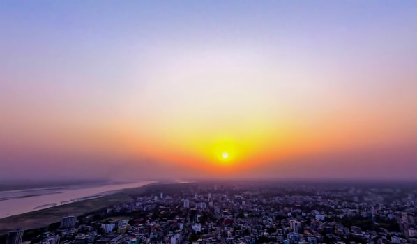 The sun setting over a city with a large body of water photo