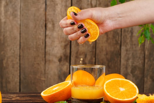 Woman hand squeezes orange juice close up photo