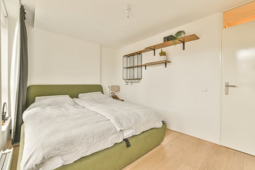 A bedroom with a bed and a green chair photo