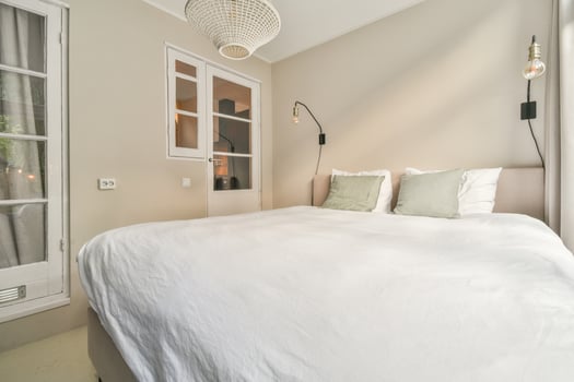 A white bed in a bedroom with a window photo